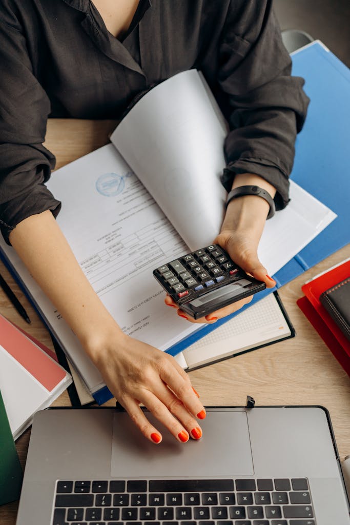 Accountant holding a calculator while working on a laptop