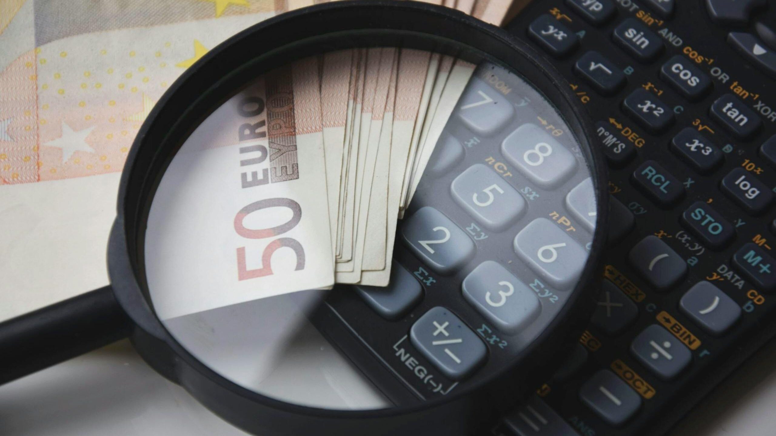 Euro bills under magnifying glass with calculator XERO Accounting