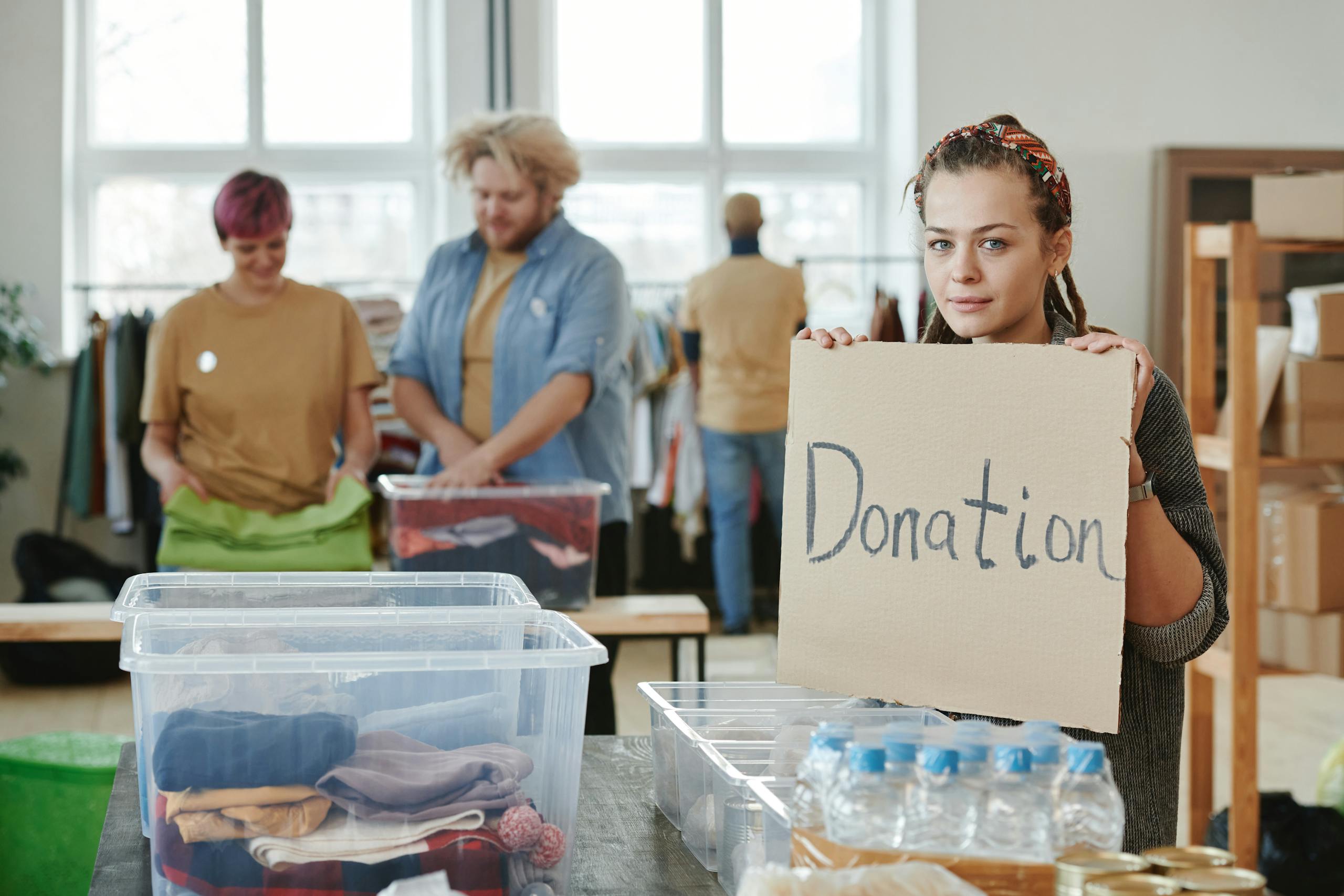 Tax Benefits for Charities - Group of volunteers organizing clothing and water donations indoors.