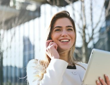 woman talking over phone holding ipad